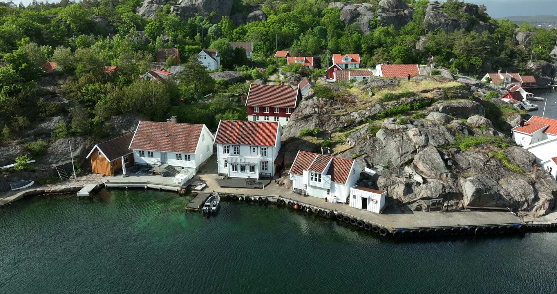 Waterfront buildings nestled against massive granite boulders, Ny-Hellesund, Norway