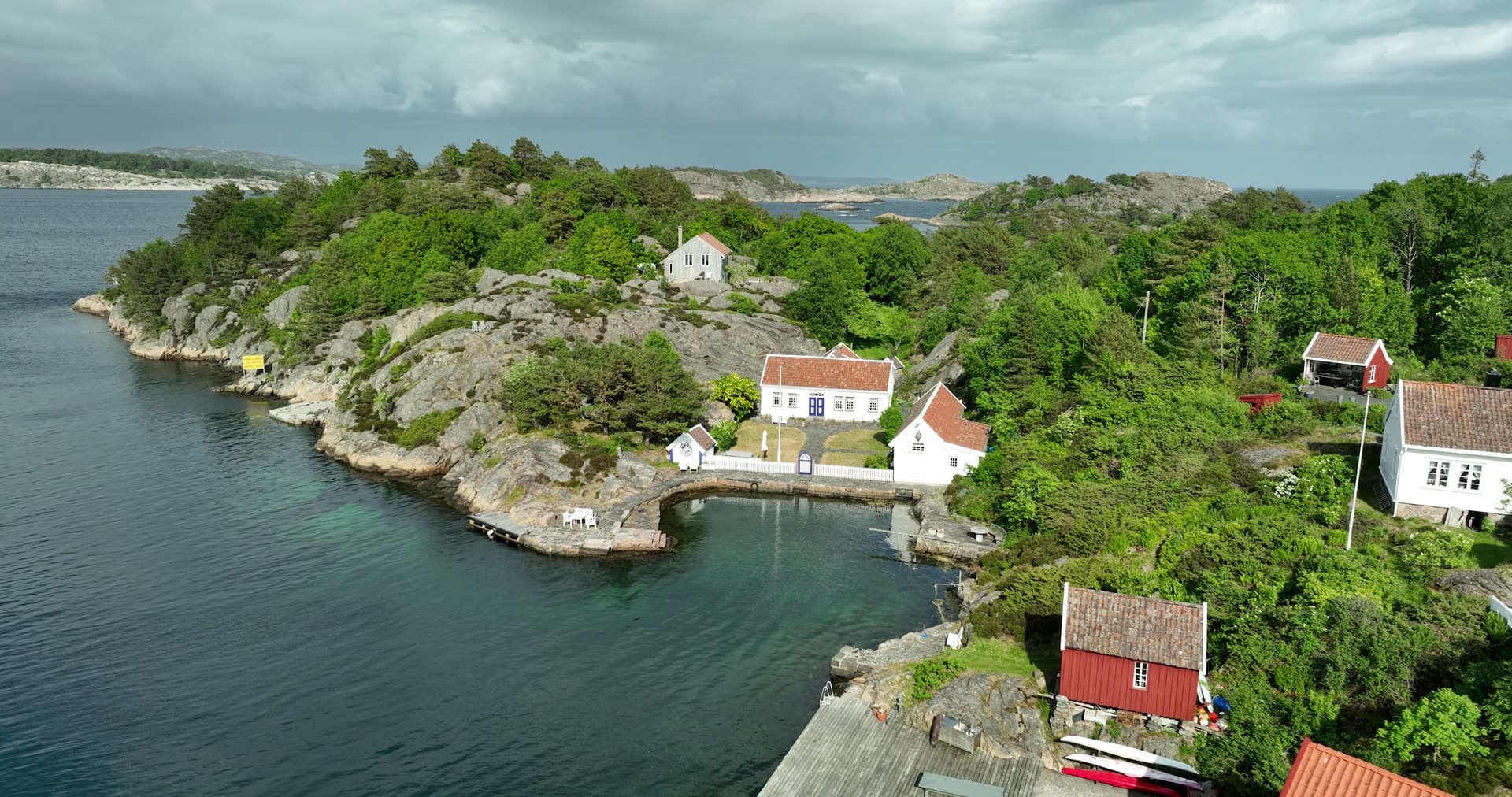 Stone harbor sheltered by forested granite headland, Ny-Hellesund, Norway