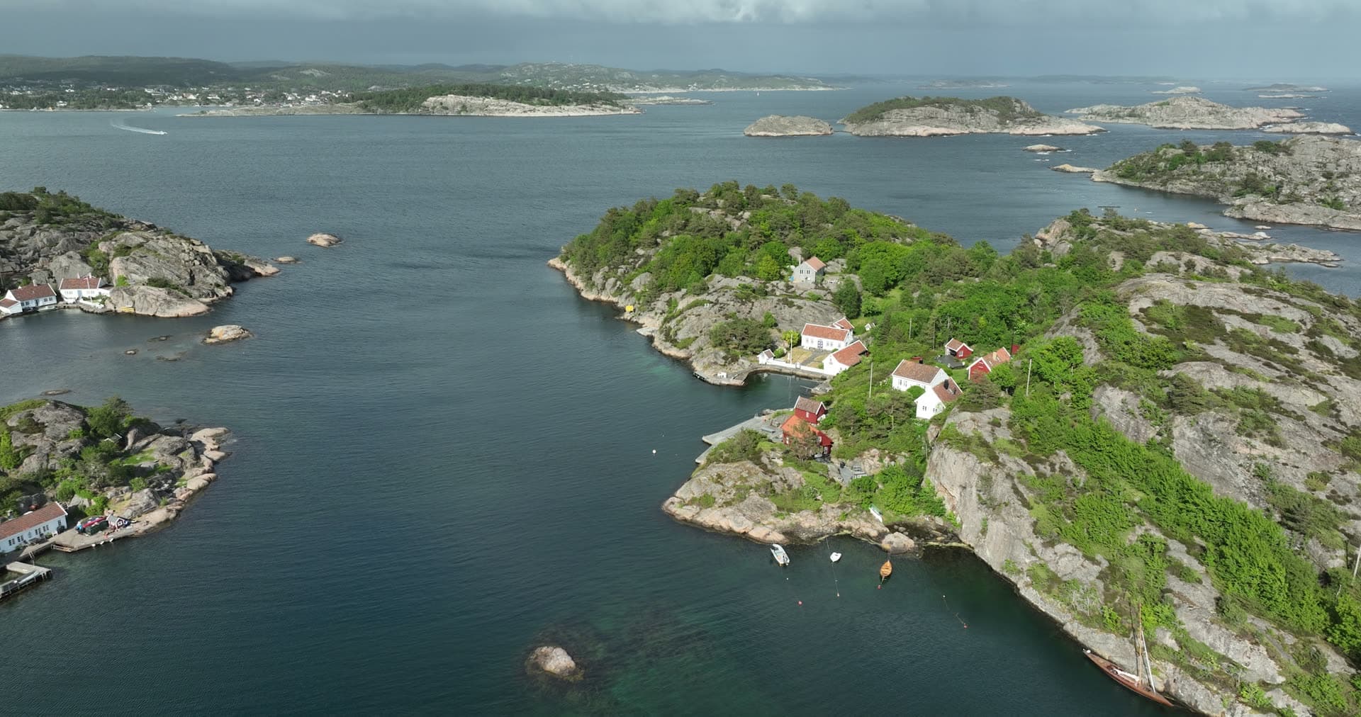 Densely forested peninsula with clustered waterfront buildings, Ny-Hellesund, Norway