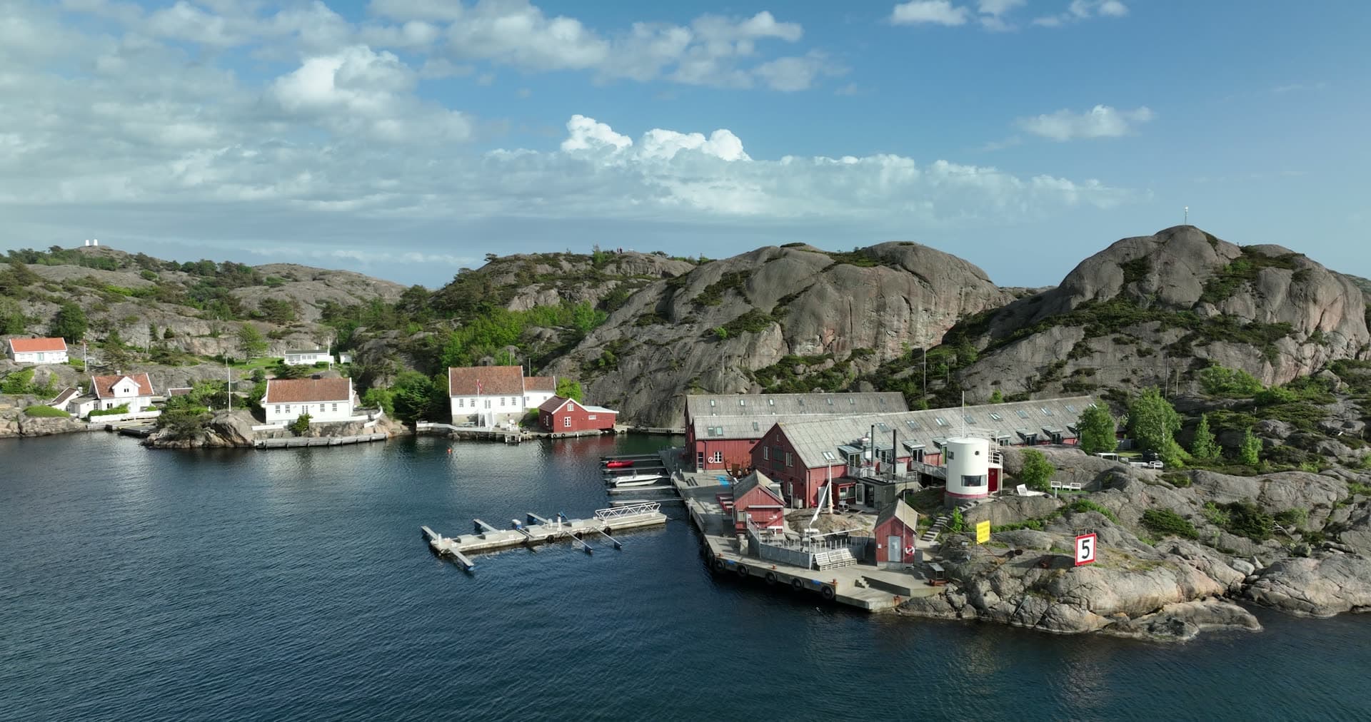 Massive granite boulders towering above waterfront buildings, Ny-Hellesund, Norway