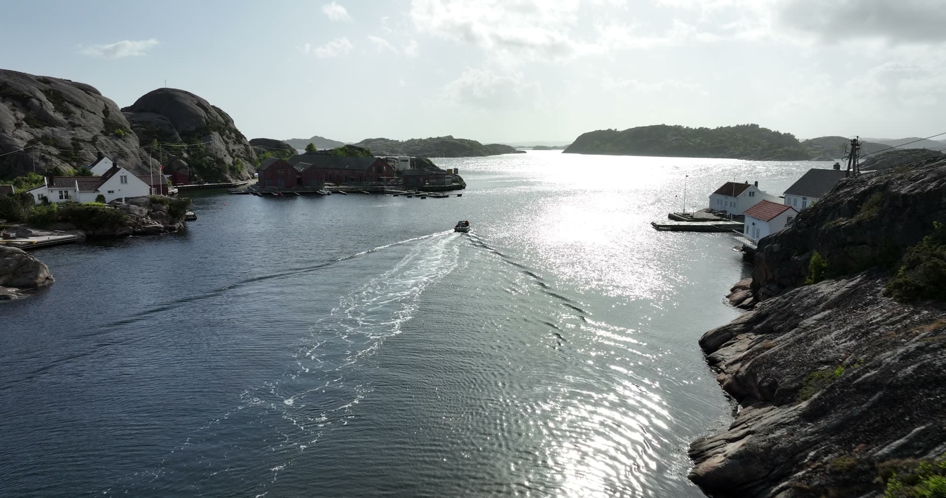 Motorboat crossing between rocky granite peninsulas, Ny-Hellesund, Norway