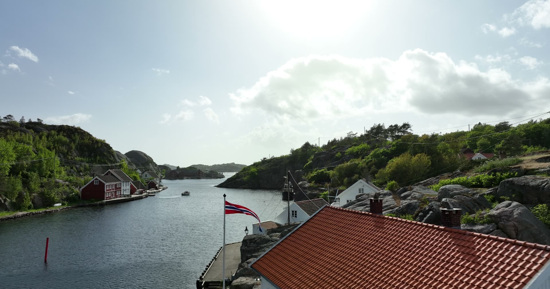 Norwegian flag and terracotta roof in foreground, Ny-Hellesund, Norway
