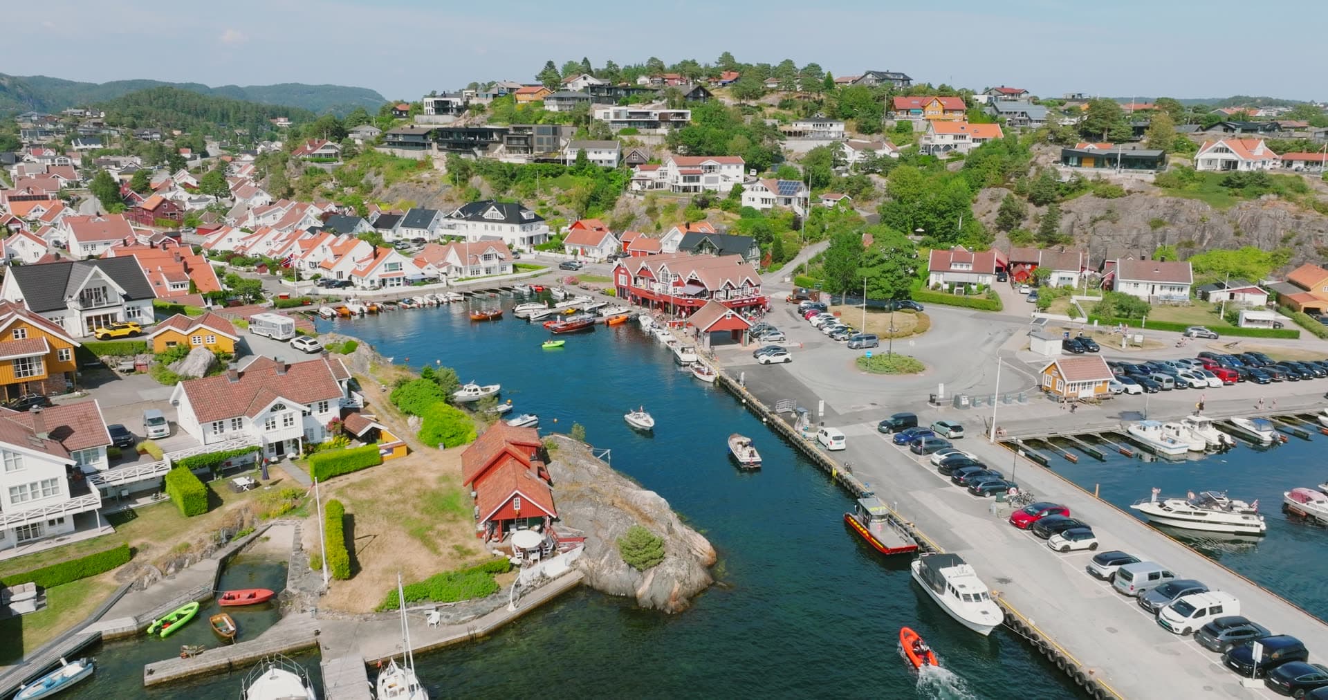 Steep hillside town sprawling above harbor basin, Høllen, Norway