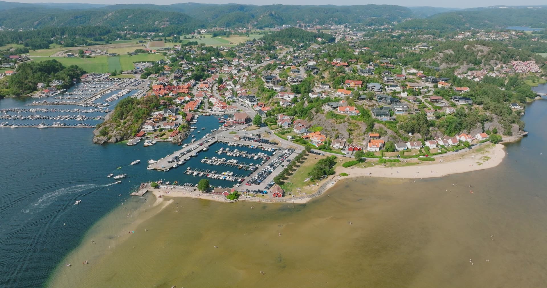 Sandy beach and moored sailboat fleet anchor, Høllen, Norway