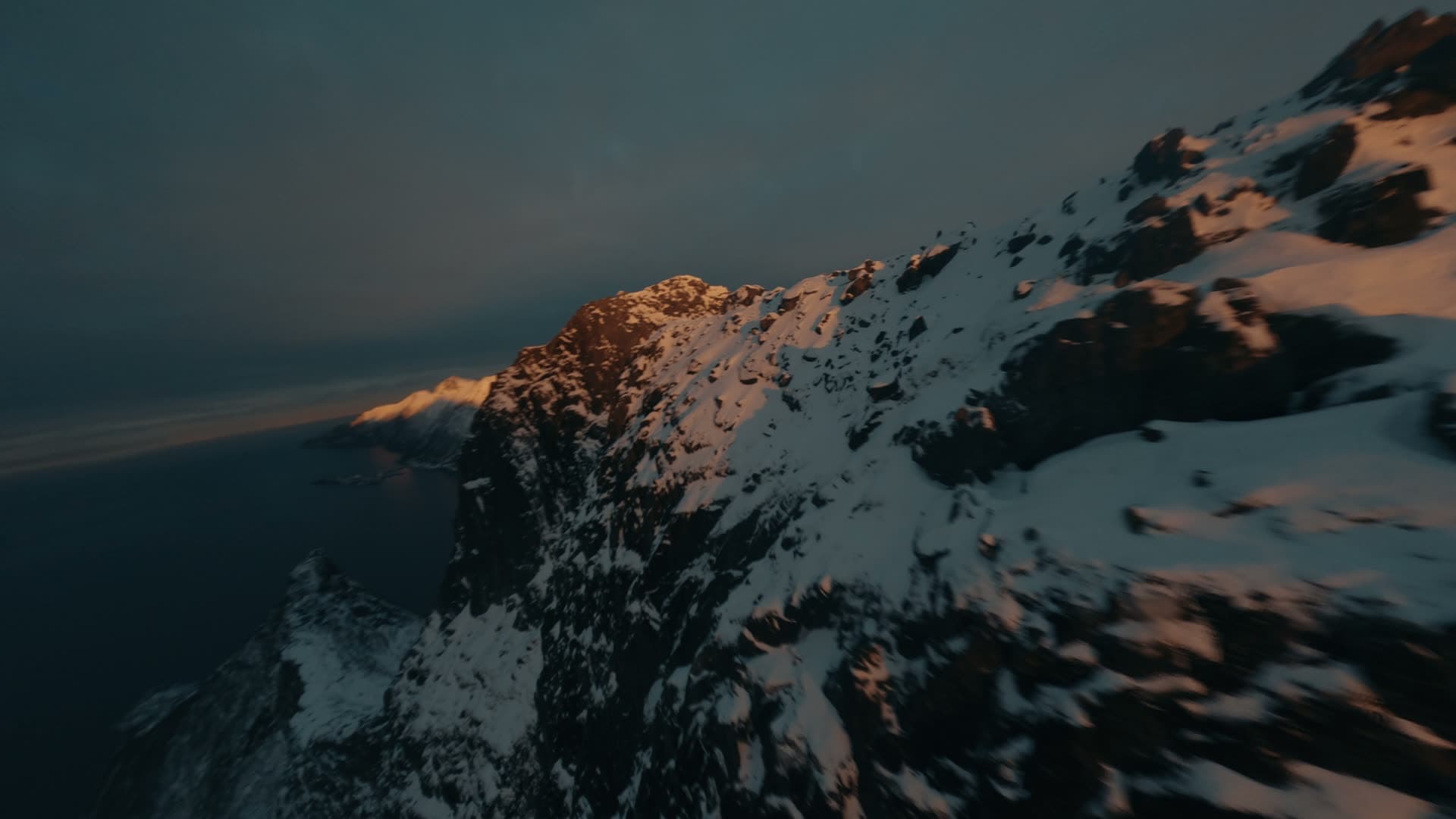 Steep snowy ridge caught in golden hour light, Senja, Norway