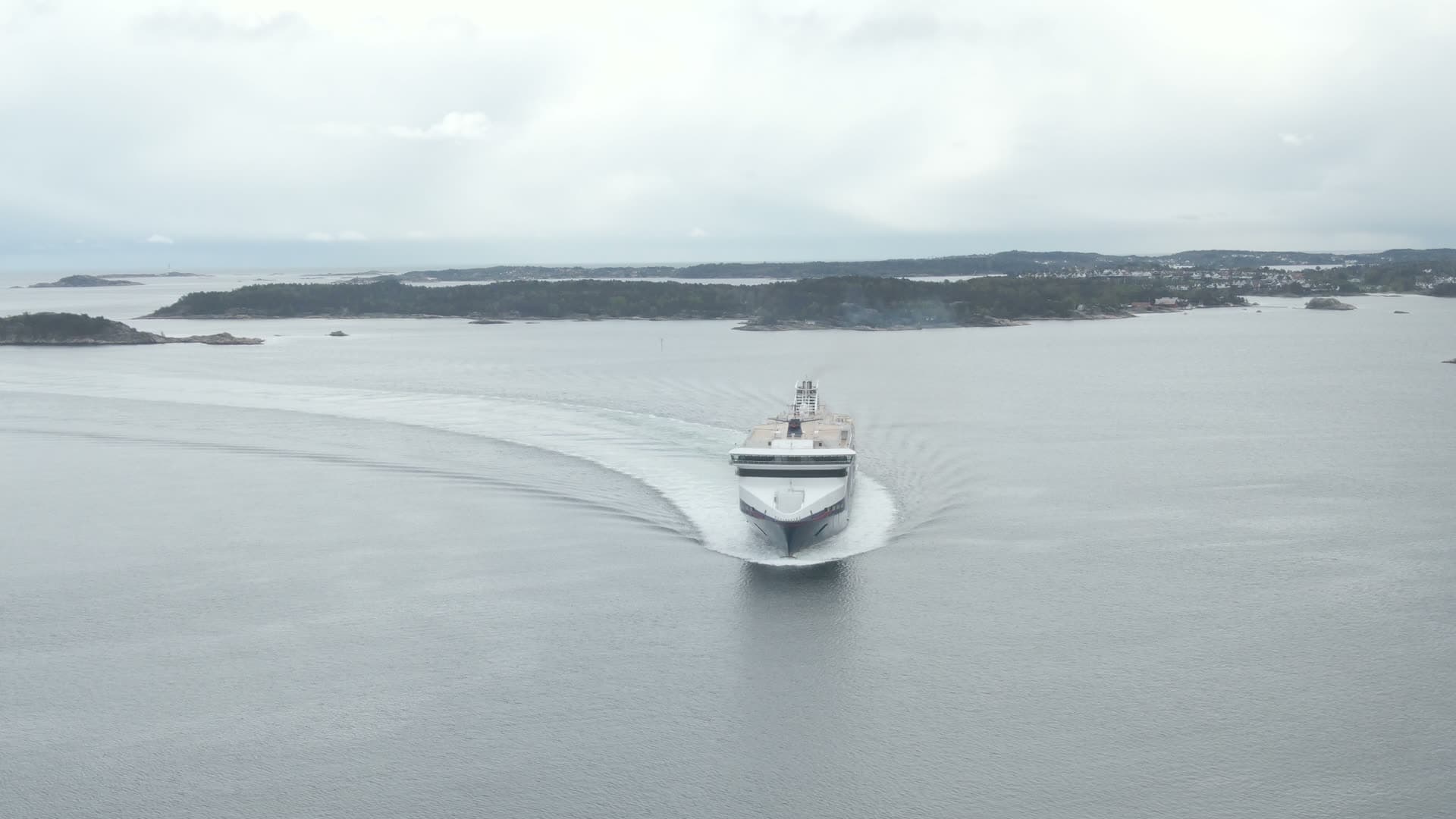 Large cruise ship departing through narrow coastal passage, Kristiansand, Norway