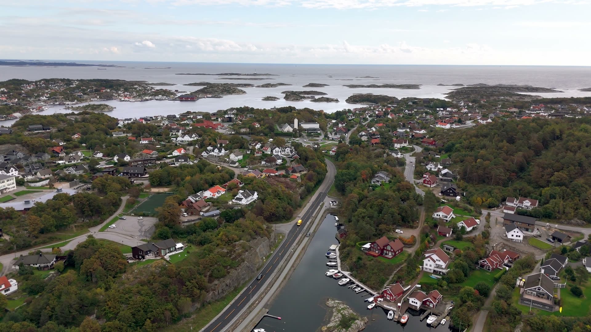 Straight road cutting through forested residential landscape, Flekkerøy, Norway