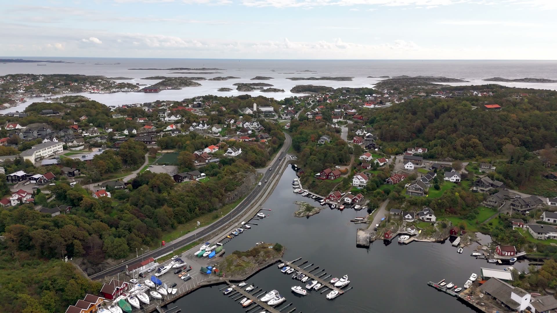 Canal dividing residential area with moored boats, Flekkerøy, Norway