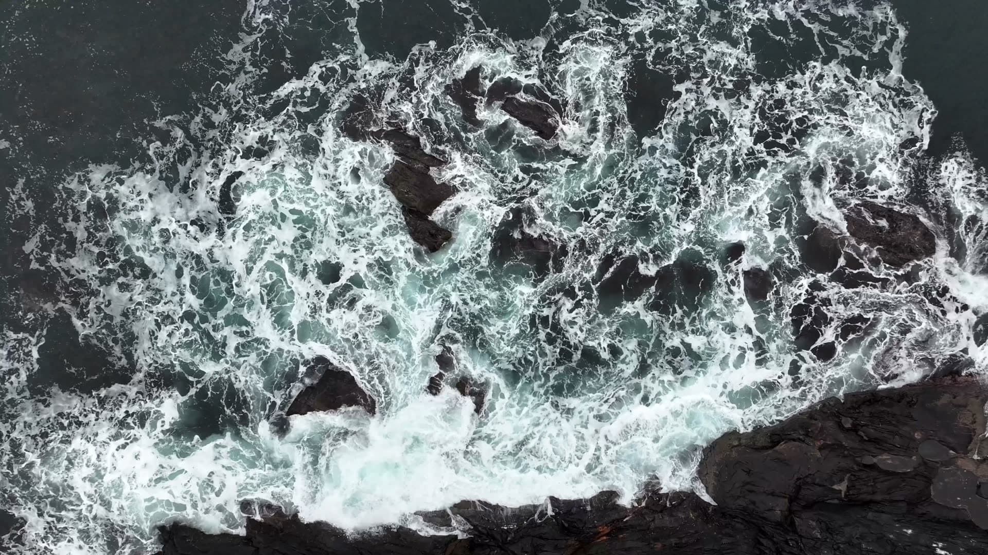 Overhead view of foaming surf breaking over coastal rocks at Ulla, Haramsøy