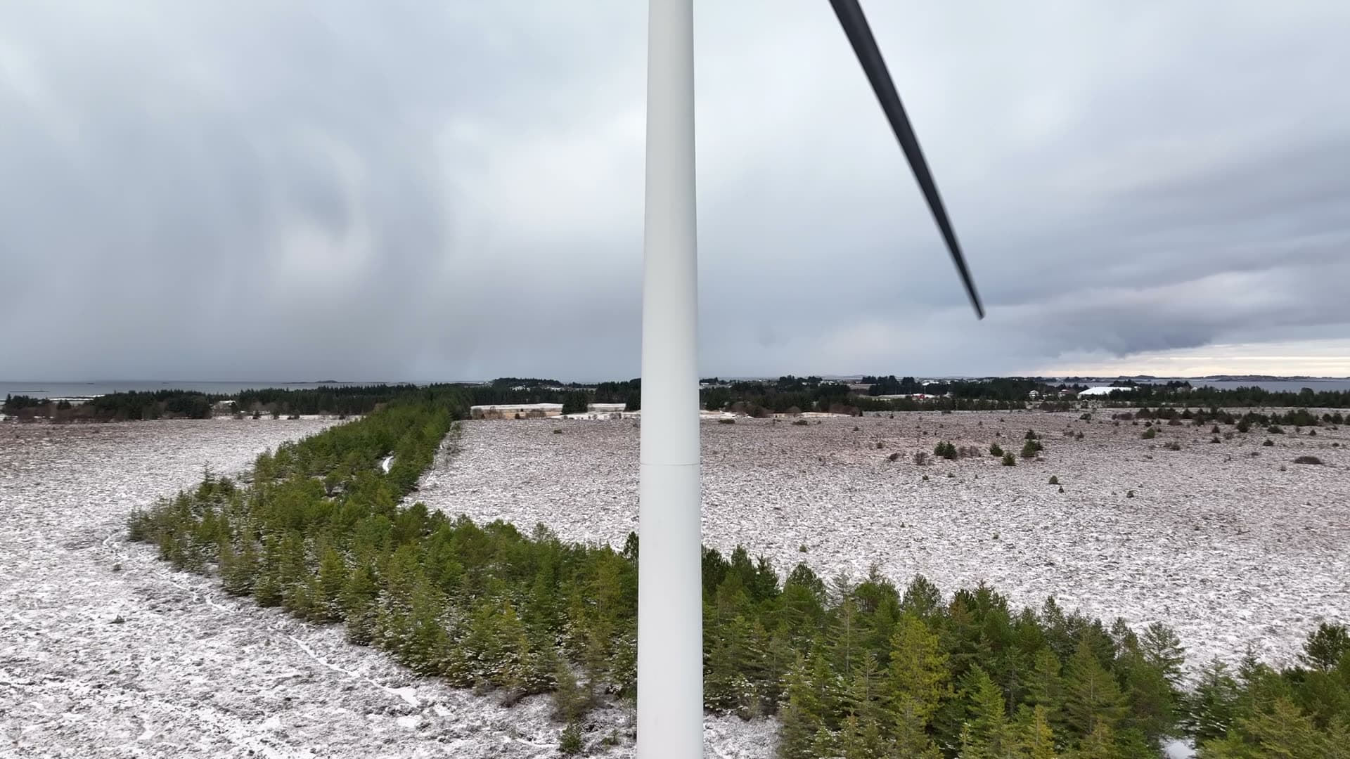 Aerial rise beside a wind turbine tower in winter, Harøy