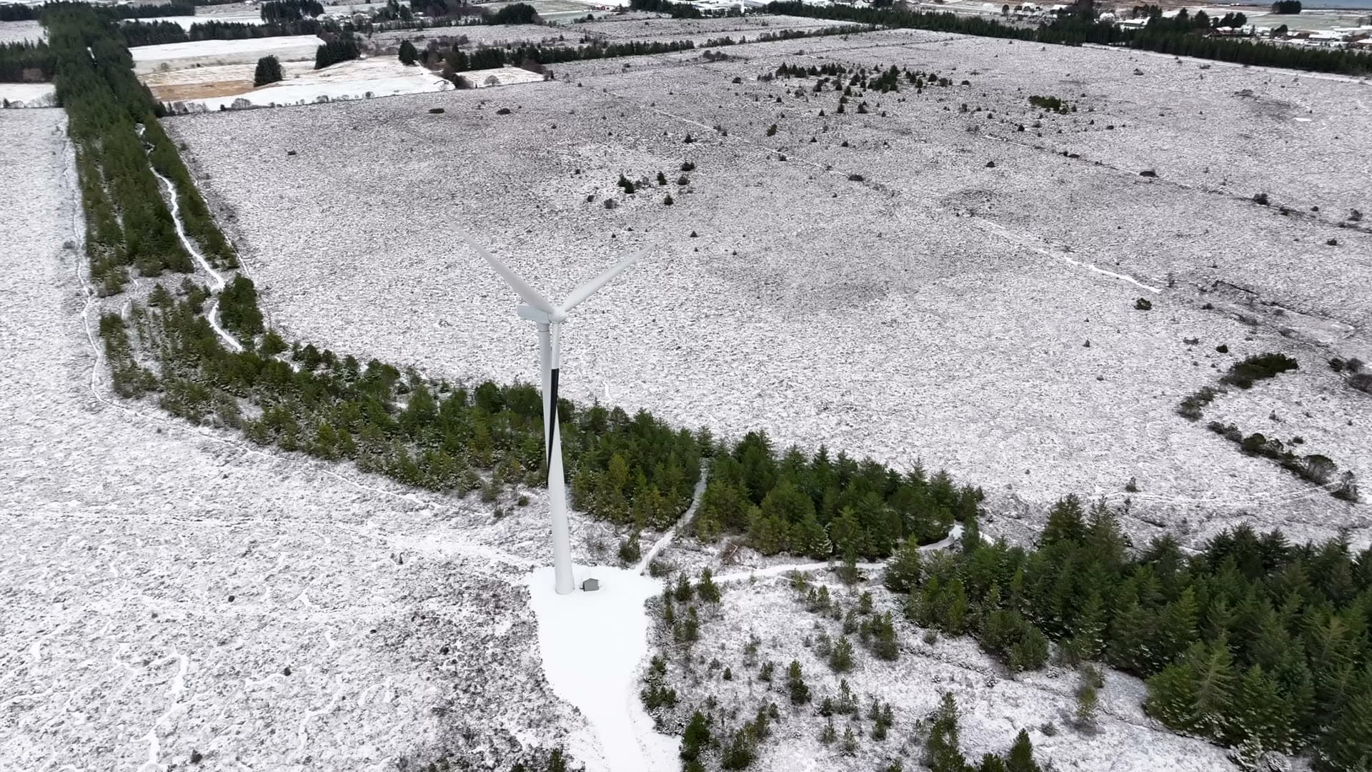 Angled aerial view of a wind turbine above a snowy clearing, Harøy