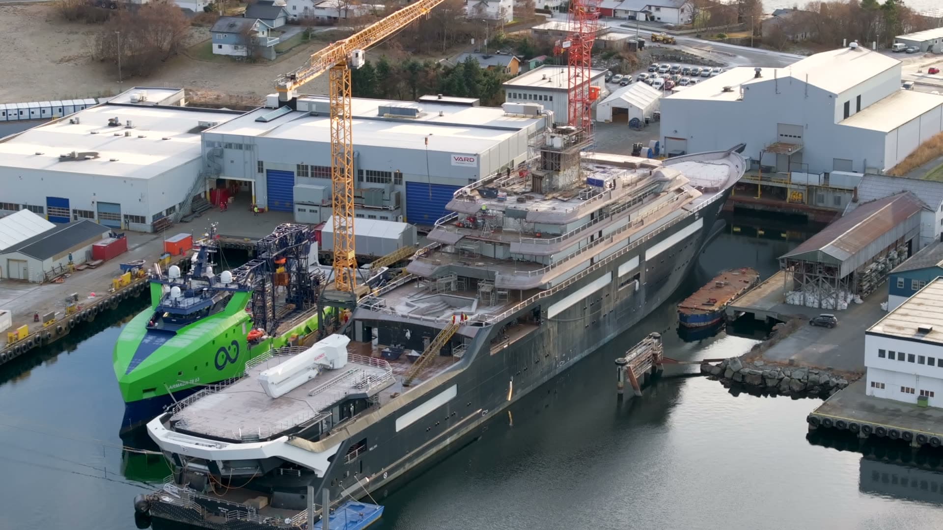 Diagonal rear view of REV Ocean and a green vessel at the shipyard