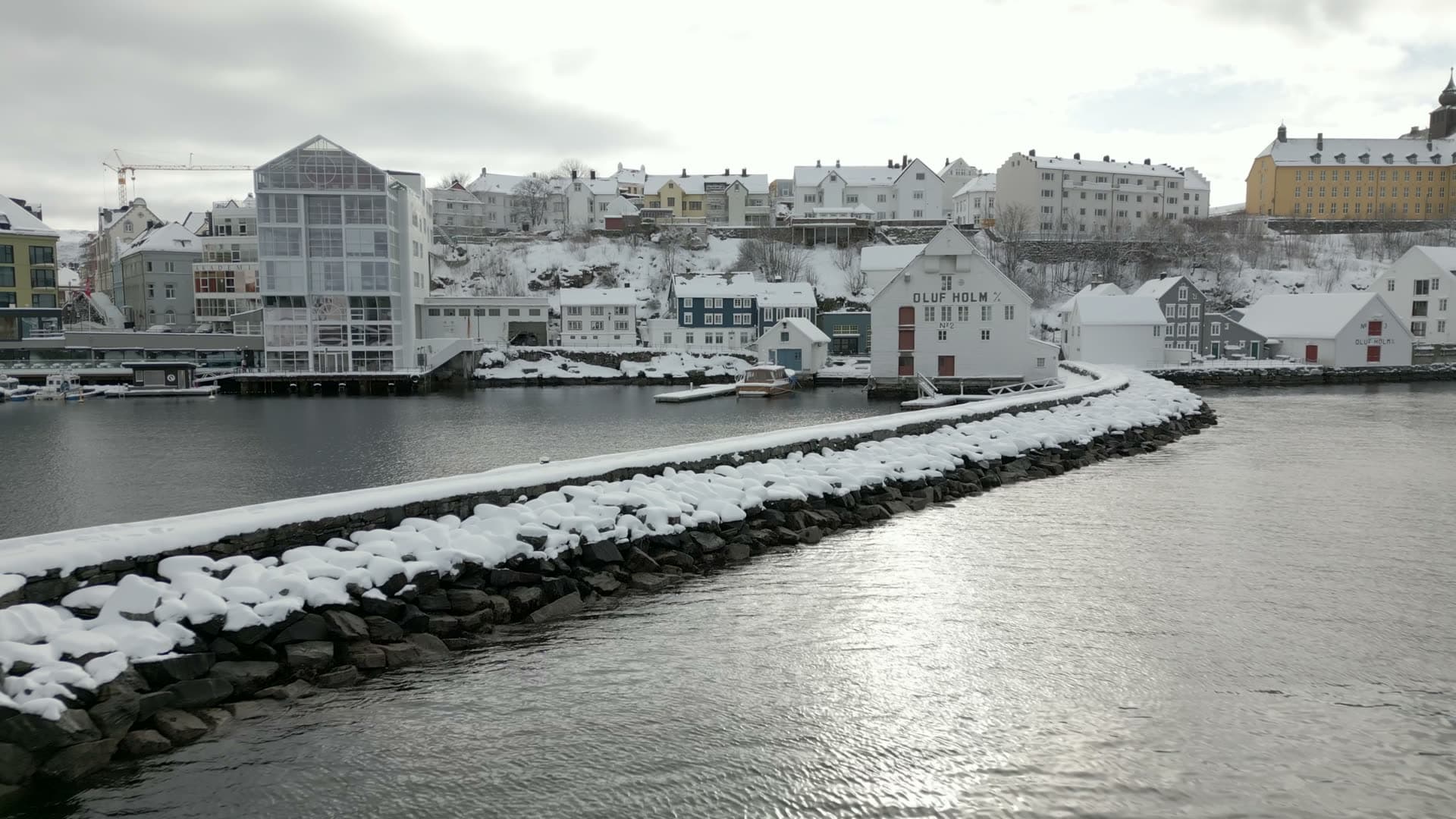 Aerial approach past Molja lighthouse toward a snowy waterfront