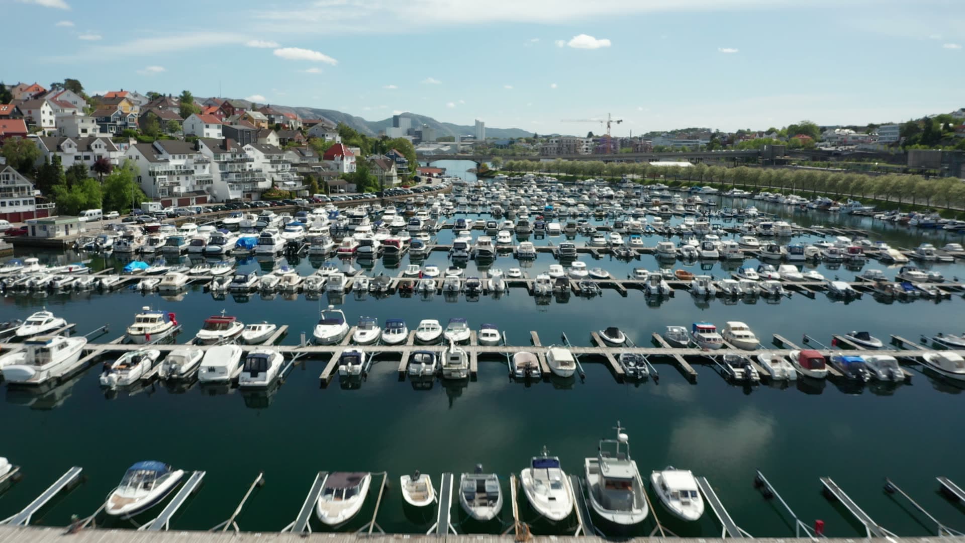 Large marina with moored boats and waterfront homes, Stavanger