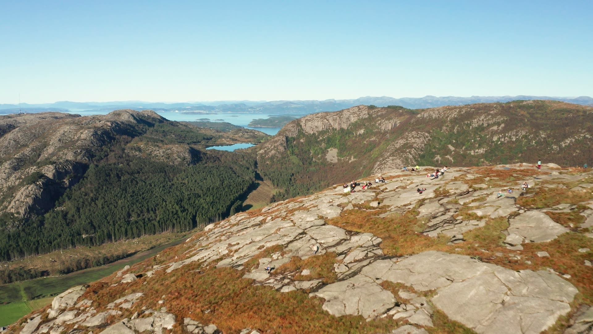 Hikers on mountain rock plateau with lake views, Dalsnuten
