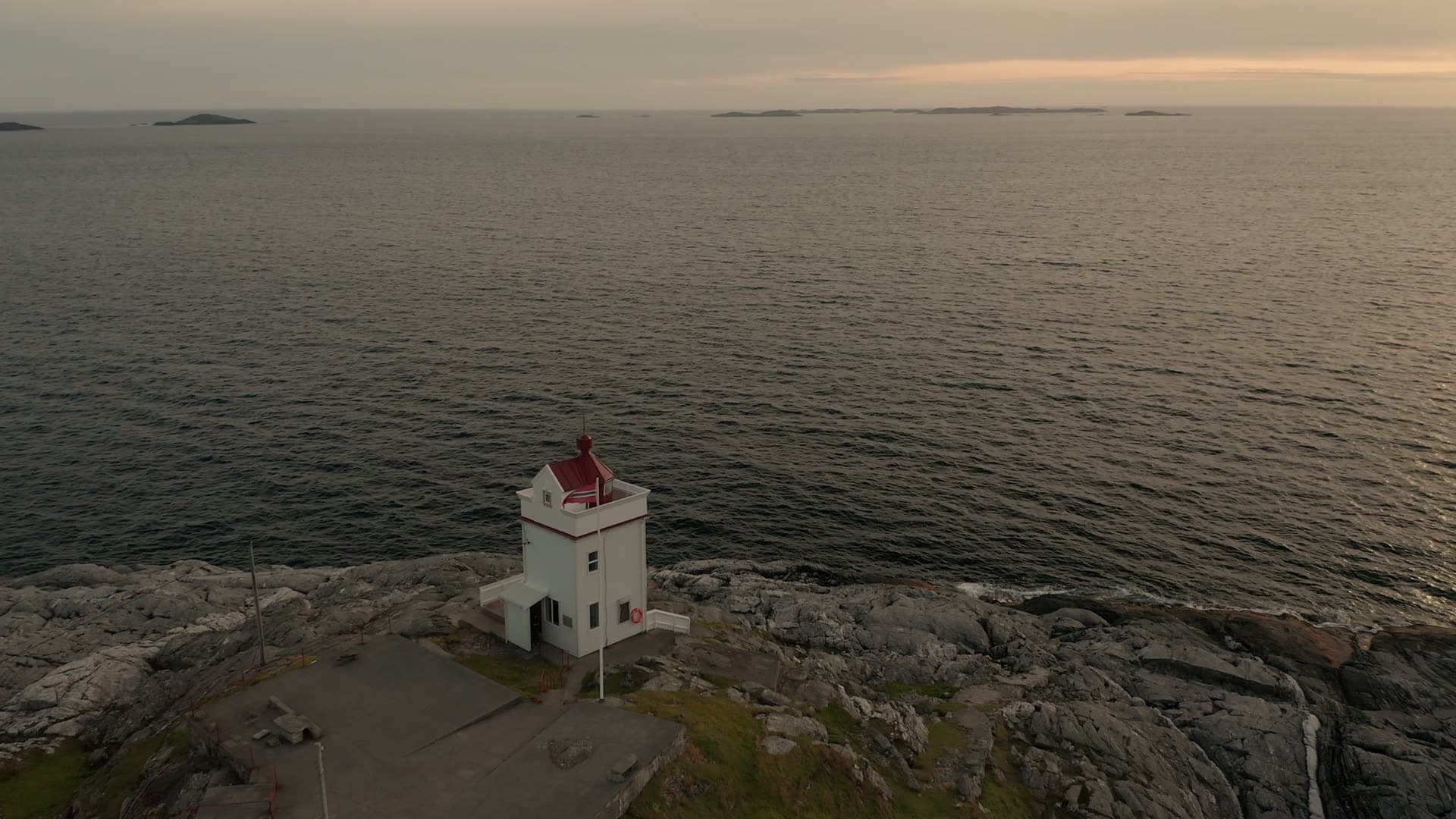 White lighthouse on rocky coast at dusk, Ryvarden fyr