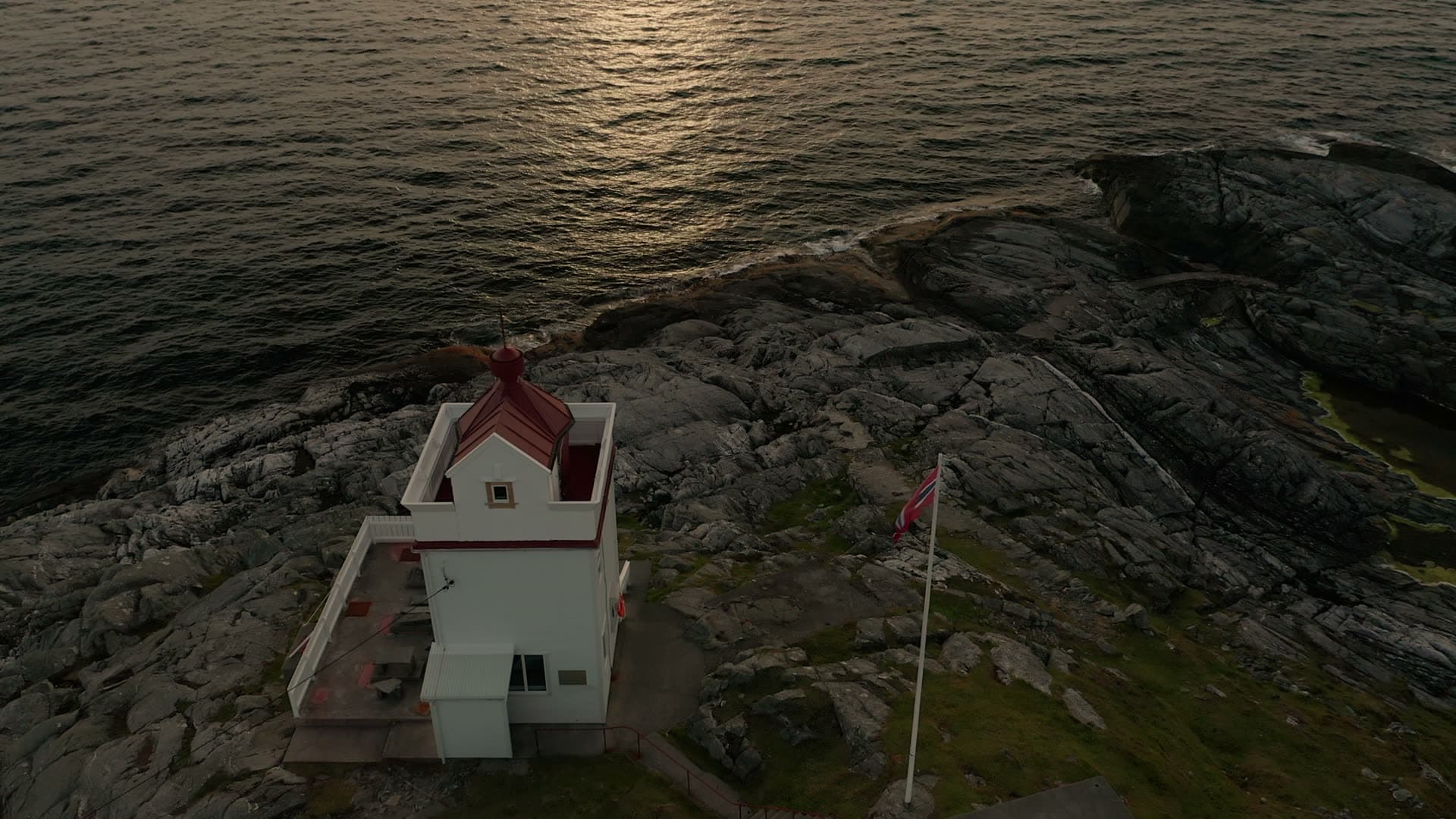 Red and white coastal lighthouse on rocky shore, Ryvarden fyr