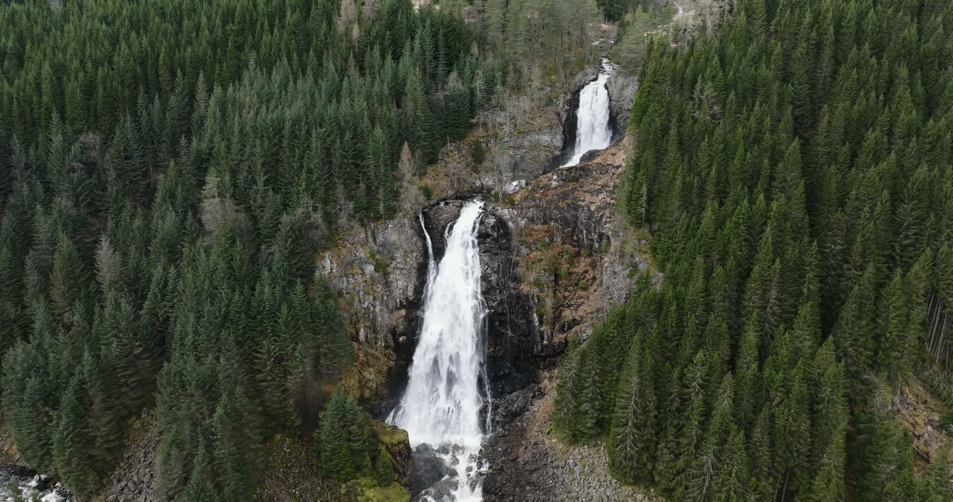 Tiered waterfall cascading through evergreen forest, Låtefossen