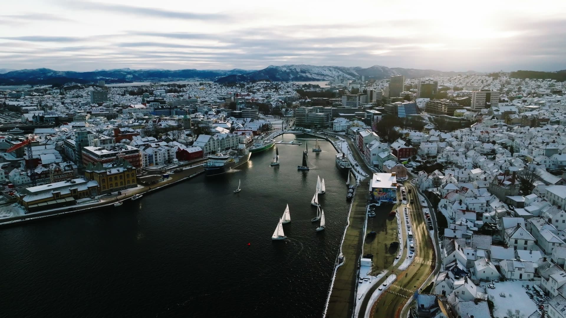 Sailboats in winter harbor with snow-covered city, Stavanger