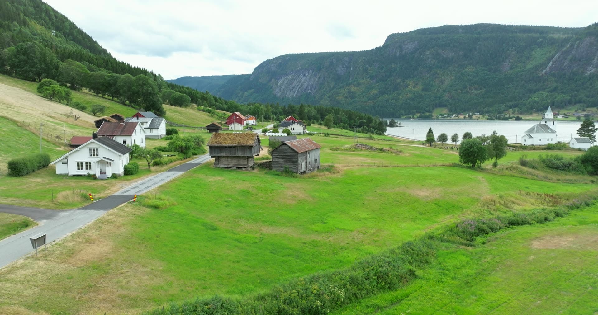 Weathered turf-roofed storage buildings in pastoral valley, Åraksbø, Bygland, Norway
