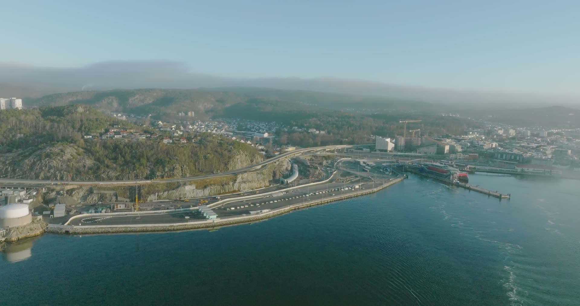 Curved coastal highway and port infrastructure in mist, Kristiansand, Norway