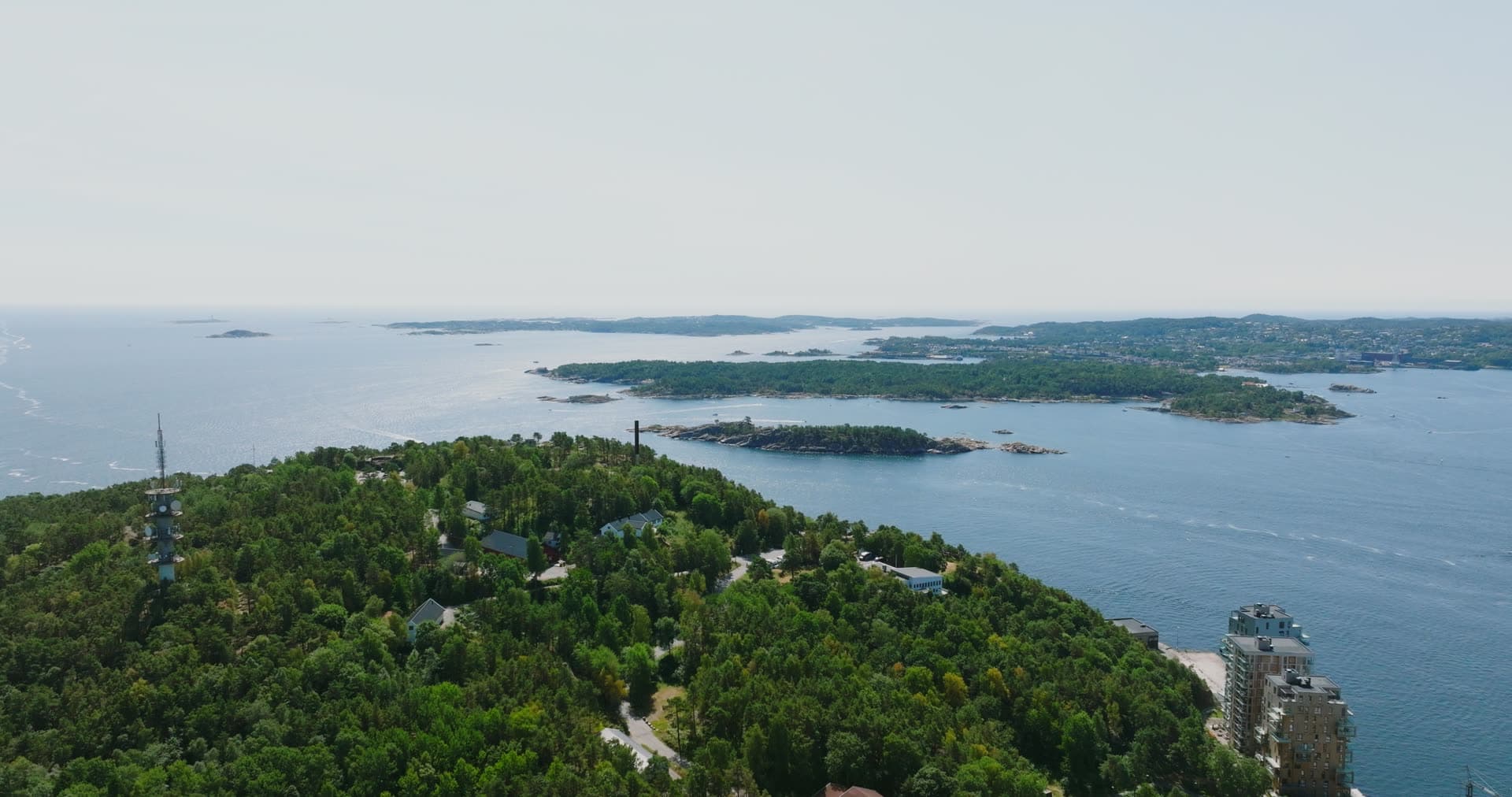 Dense forest with tower and scattered buildings overlooking archipelago, Kristiansand, Norway