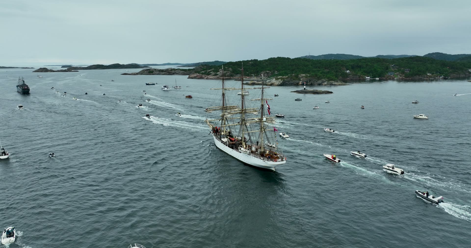 Tall ship surrounded by escort boats in harbor, Kristiansand, Norway