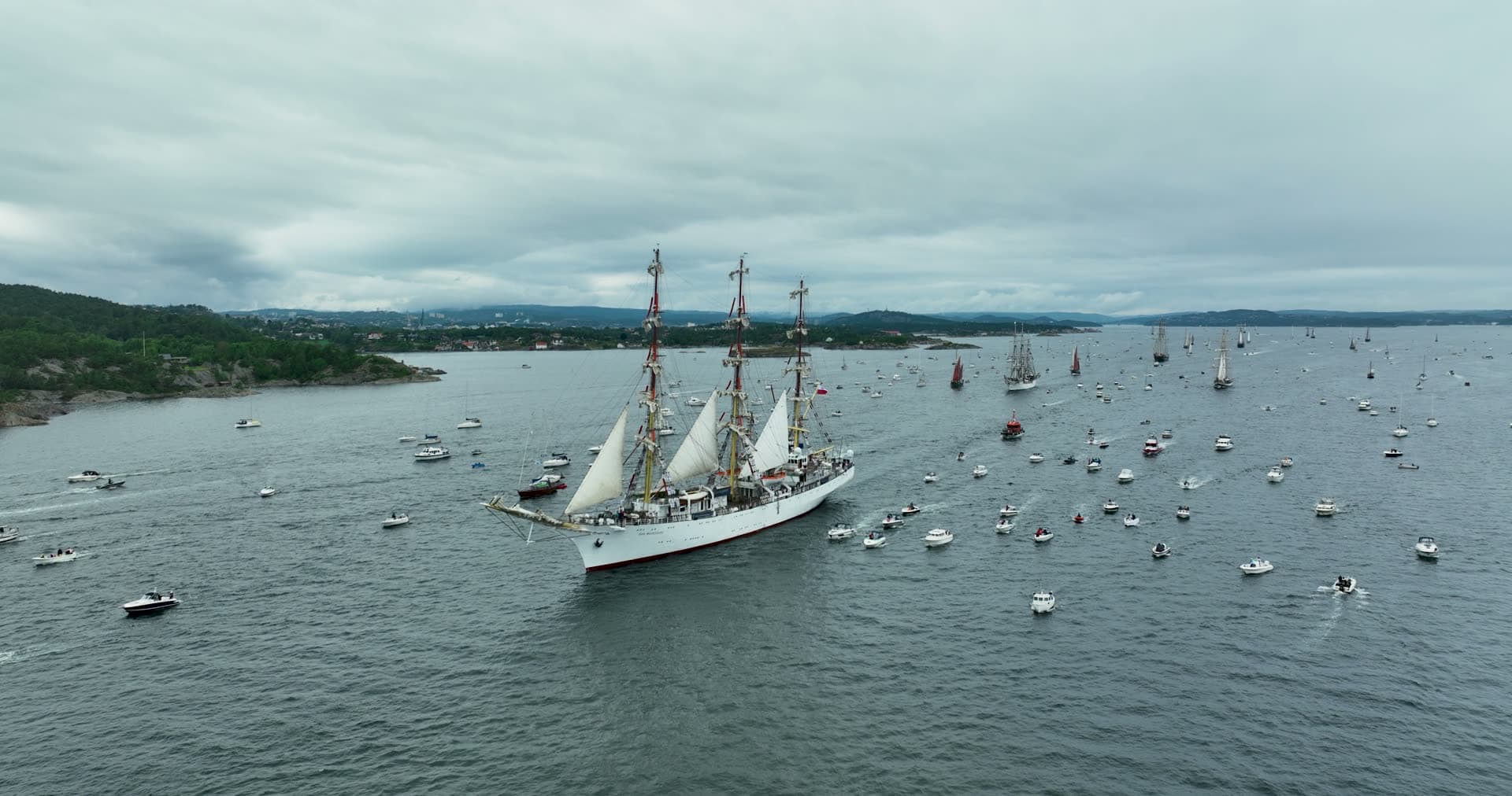 Tall ship with three masts anchored among moored vessels, Kristiansand, Norway
