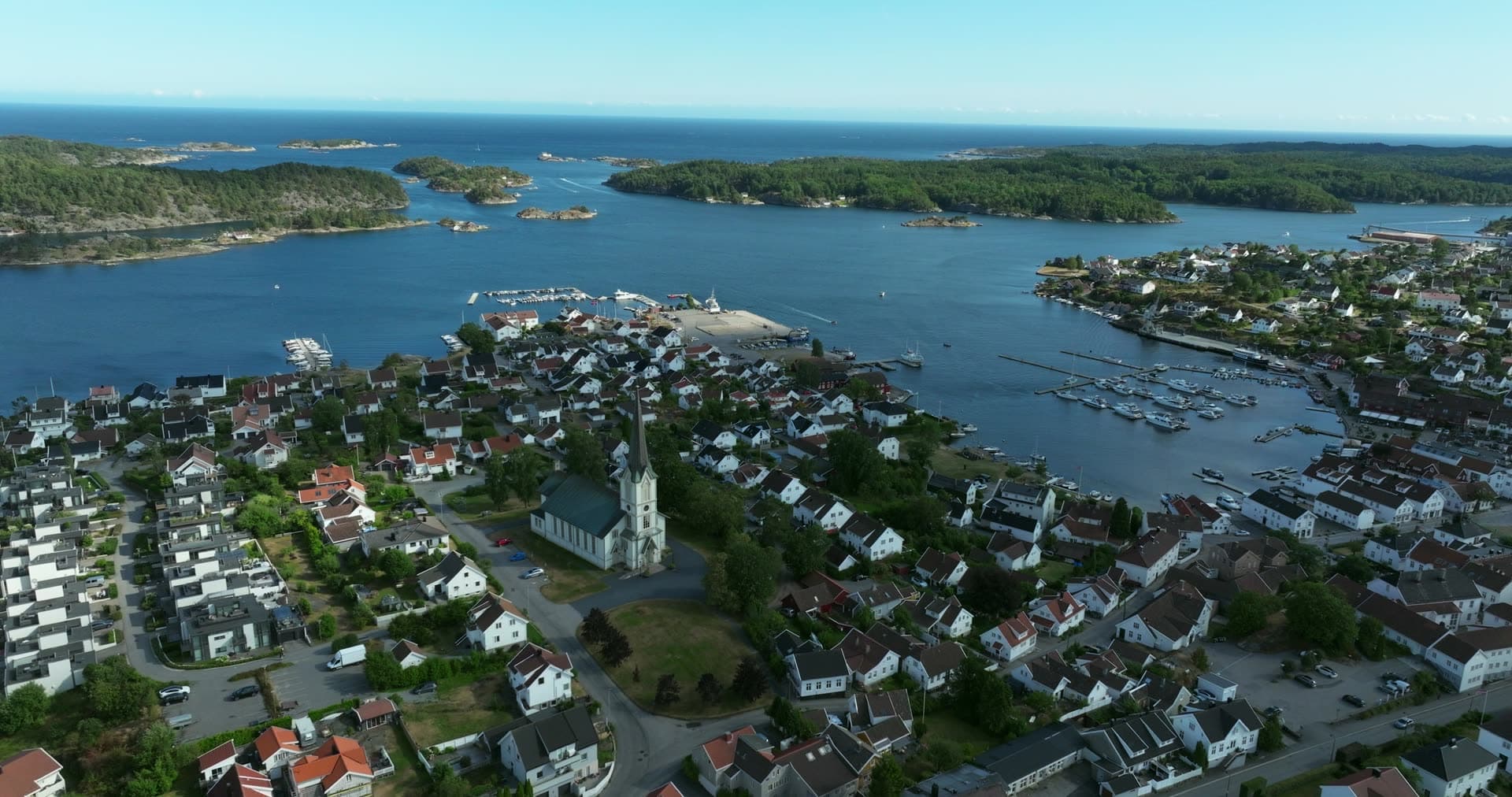 White church spire rising above clustered waterfront town, Lillesand, Norway