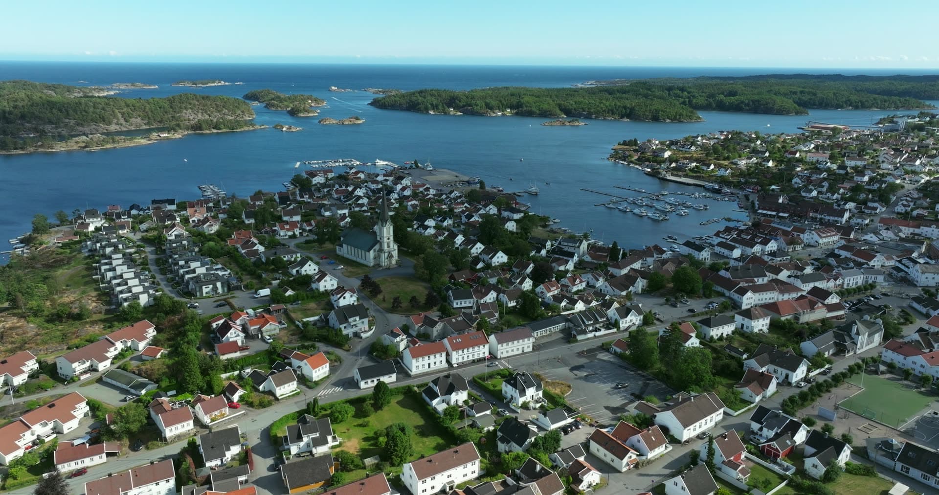 White church spire dominating the peninsular town center, Lillesand, Norway