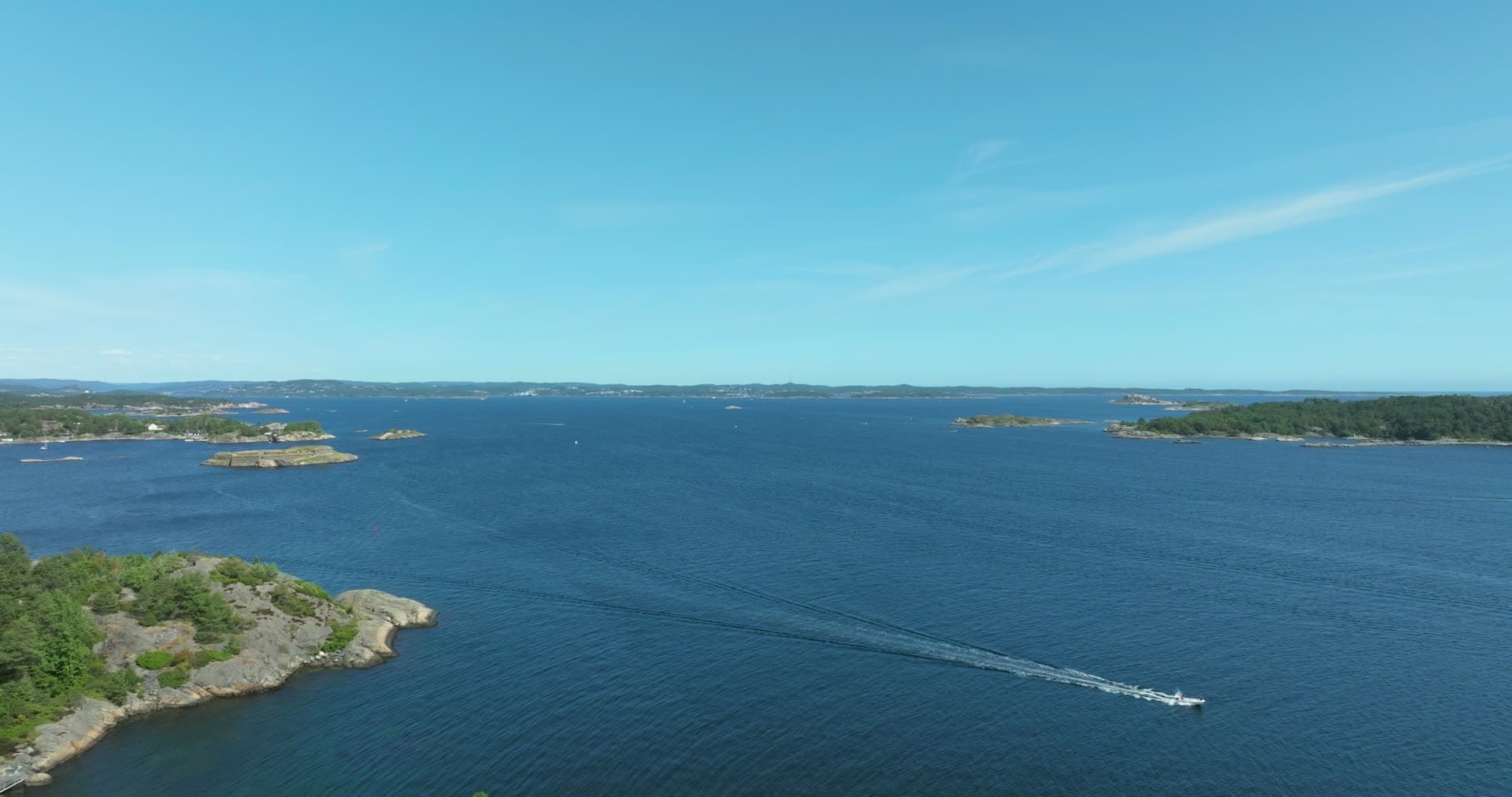 Speedboat crossing vast blue archipelago waters, Skålevik, Norway
