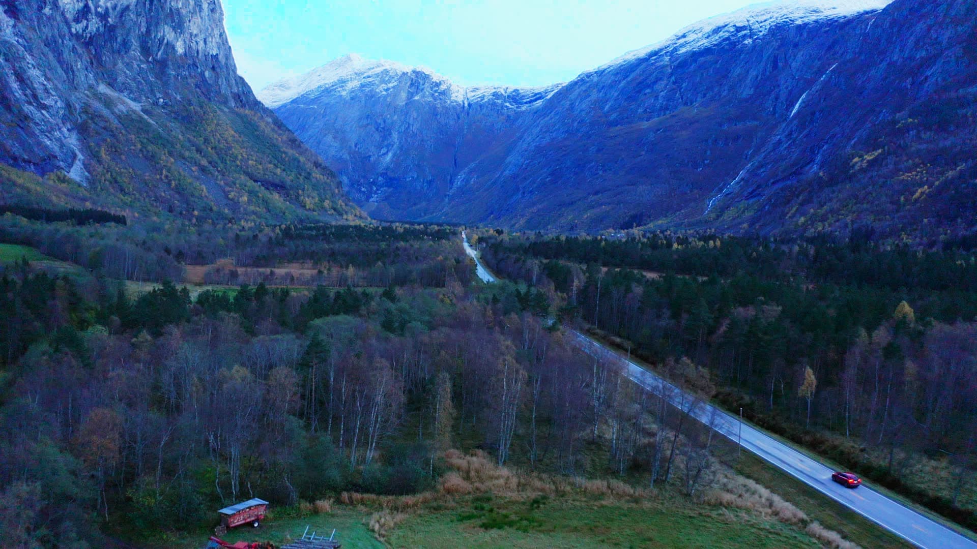 Valley road past fields below snowy peaks, Trollstigen, Norway